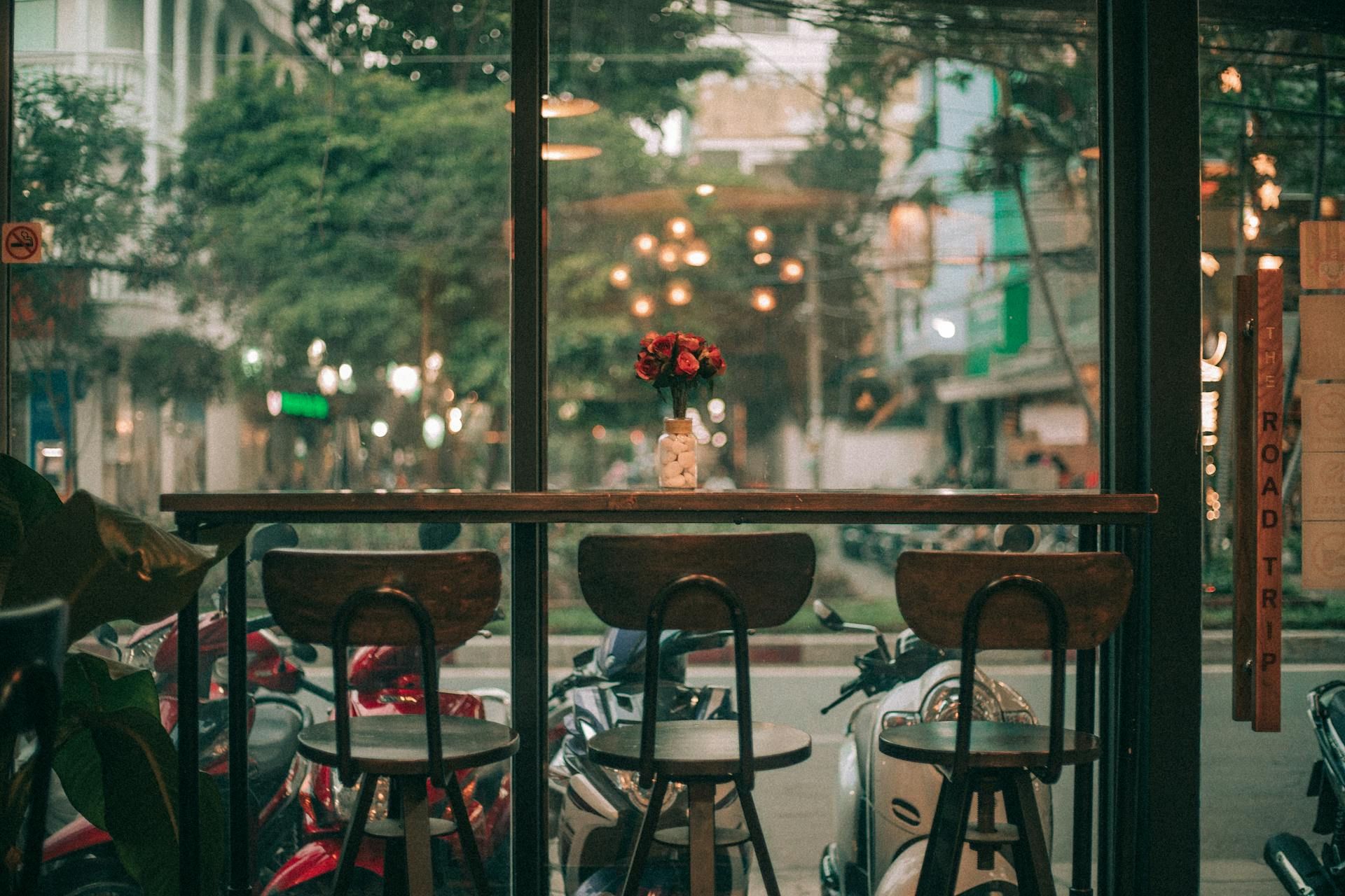 Window seating in a quiet café overlooking a street with parked motorbikes, representing the global discovery of local coffee culture.