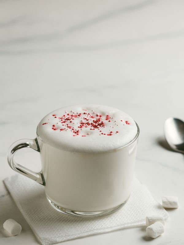 Babyccino in a small clear cup with thick milk foam and a light dusting on top.