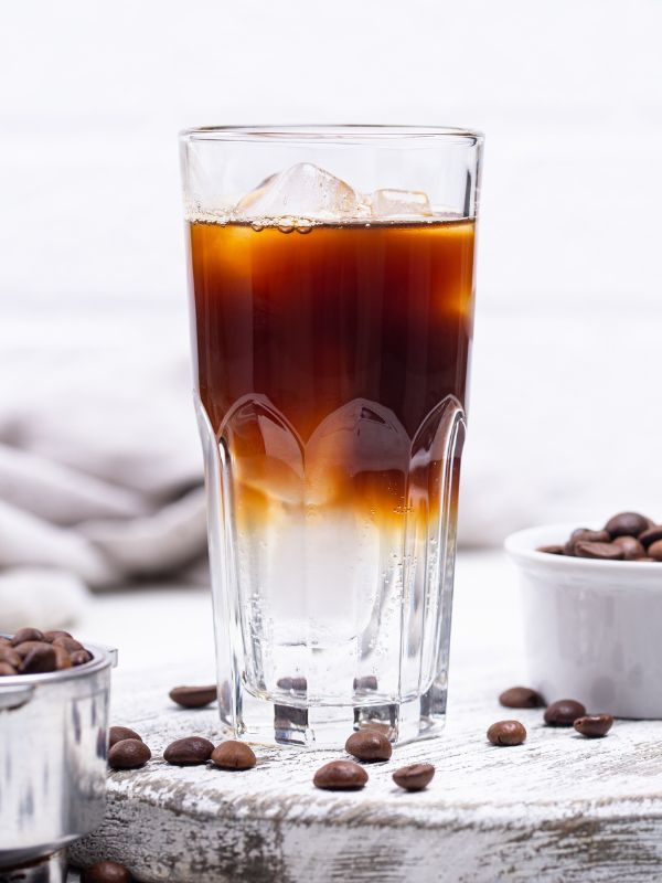 Espresso tonic in a tall glass with ice, showing a dark espresso layer over clear tonic water.